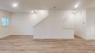 Located in Charlotte, NC, this contemporary multi-story home offers a thoughtfully designed layout spread across four levels. The entry-level garage provides convenient parking and utility space, including an electric water heater. The main living floor features a bright, open-concept area combining the living room, dining room, and kitchen. The kitchen is outfitted with white shaker cabinetry, stainless steel appliances, a central island with a white countertop and pendant lighting, and light hardwood flooring that flows throughout the home. Clean white walls and recessed lighting create a crisp, modern ambiance. Stairways connect the levels with a simple, elegant design featuring light wood treads and white risers. The bedrooms are well-proportioned, each benefiting from natural light through blinded windows and ceiling fans for comfort. The primary bedroom is a generous retreat accompanied by a sleek en-suite bathroom showcasing a glass-enclosed tiled shower, marble-style tile flooring, white vanity cabinetry, and matte black hardware. Additional bathrooms echo this refined aesthetic. With six closets distributed throughout, storage is plentiful. The home's clean, neutral palette and consistent hardwood-style flooring tie each level together cohesively.