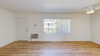 Located on Burbank Boulevard in the Tarzana neighborhood of Los Angeles, this well-appointed single-floor unit offers a clean, modern aesthetic defined by bright white walls and light wood-toned flooring that runs seamlessly throughout the space. The open-plan living, dining, and kitchen area forms the heart of the unit, creating a cohesive and functional layout. The kitchen is well-equipped with crisp white cabinetry extending to the ceiling for ample storage, a stainless steel refrigerator, a white range, a sink with under-counter storage, and a peninsula that provides additional counter space and naturally separates the kitchen from the living area. The living area receives natural light through a large window fitted with vertical blinds, offering views of the surrounding greenery, and includes a wall-mounted HVAC unit for year-round comfort. The bedroom is a comfortable, sun-lit room featuring a full-width mirrored sliding closet that enhances the sense of space. The bathroom is outfitted with a tub and shower combination enclosed by sliding glass doors, a toilet, and a vanity. A ceiling fan in the living area and dedicated entry door with thermostat controls complete this efficiently designed and move-in ready unit.
