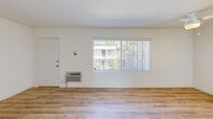 Located on Burbank Boulevard in the Tarzana neighborhood of Los Angeles, this well-appointed single-floor unit offers a clean, modern aesthetic defined by bright white walls and light wood-toned flooring that runs seamlessly throughout the space. The open-plan living, dining, and kitchen area forms the heart of the unit, creating a cohesive and functional layout. The kitchen is well-equipped with crisp white cabinetry extending to the ceiling for ample storage, a stainless steel refrigerator, a white range, a sink with under-counter storage, and a peninsula that provides additional counter space and naturally separates the kitchen from the living area. The living area receives natural light through a large window fitted with vertical blinds, offering views of the surrounding greenery, and includes a wall-mounted HVAC unit for year-round comfort. The bedroom is a comfortable, sun-lit room featuring a full-width mirrored sliding closet that enhances the sense of space. The bathroom is outfitted with a tub and shower combination enclosed by sliding glass doors, a toilet, and a vanity. A ceiling fan in the living area and dedicated entry door with thermostat controls complete this efficiently designed and move-in ready unit.