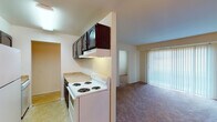 Located at 2420 Tate Springs Rd in Lynchburg, Virginia, this single-floor unit offers a practical and straightforward layout across several well-defined spaces. The galley-style kitchen is efficiently arranged with dark wood cabinetry overhead, a white electric coil-burner range, a full-size refrigerator, and light-toned countertops. Tile flooring runs through the kitchen, which opens toward the living area. The living space features carpet flooring and a sliding glass door fitted with vertical blinds, allowing natural light to filter in. A separate dining area is distinguished by two-tone walls with a chair rail, complemented by a modest chandelier overhead and tile flooring. The bedrooms are carpeted and receive natural light through blinds-covered windows. One bedroom features a spacious walk-in closet with dual shelving sections, offering generous storage capacity. A second bedroom also includes closet access. Two bathrooms are present, each featuring a tub-shower combination with light blue tile surrounds, a vanity with a mirrored medicine cabinet, and standard fixtures. The overall layout is functional and straightforward, suited for everyday living.