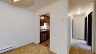 Located at 4567 S Whitnall Ave in St. Francis, Wisconsin, this single-floor unit offers a well-organized layout designed for comfortable, everyday living. The kitchen is efficiently arranged in a galley style, featuring rich dark wood cabinetry, granite-look countertops, a stainless steel refrigerator, range, dishwasher, and a single-basin sink — all set atop durable wood-look vinyl plank flooring that adds warmth to the space. The living area is open and bright, highlighted by a large sliding glass door that invites natural light and provides views of the surrounding green outdoor space. Plush wall-to-wall carpeting extends throughout the living and bedroom areas, contributing to a cozy, residential feel. The bedroom is a well-proportioned, quiet retreat with a window offering outdoor views, a baseboard heating unit, and a closet with louvered doors. The bathroom is thoughtfully finished with large-format tile surrounding the soaking tub and shower combination, complemented by wood-look vinyl flooring that ties back to the kitchen aesthetic. Throughout the unit, clean white walls, consistent flooring transitions, and dark wood doors and trim create a cohesive and neutral design palette suitable for a variety of personal styles.
