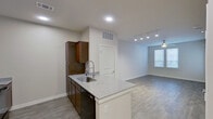 This single-floor unit is designed with a clean, modern aesthetic and a practical open-concept layout. The kitchen serves as the centerpiece, featuring rich dark-wood cabinetry that extends to the ceiling, granite-look countertops, and a peninsula with an undermount sink and a sleek pull-down faucet. Black appliances, including a refrigerator, range, and microwave, provide a cohesive, contemporary look. The peninsula transitions seamlessly into the living area, which is finished with durable hardwood-style flooring and illuminated by a combination of recessed lighting and a track lighting system. A ceiling fan adds comfort, while a window with blinds allows natural light to fill the space.

The bedroom is a calm, private retreat, carpeted for comfort and brightened by two windows with blinds. The bathroom is well-appointed with a tiled tub-shower combination, a single vanity with an integrated sink, a large mirror, and hardwood-style flooring that ties the space together. Throughout the unit, neutral wall tones, clean white trim, and consistent finishes create a cohesive and inviting atmosphere.