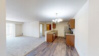 This well-appointed 2-bedroom, 2-bathroom residence in Williston, North Dakota offers a practical and comfortable single-floor layout. The open-concept living and kitchen area serves as the heart of the home, featuring warm wood-toned cabinetry, granite countertops, and a peninsula that doubles as a breakfast bar. Stainless steel appliances — including a refrigerator, range, and microwave — complement the kitchen's functional design. Hardwood-style flooring runs through the kitchen and dining area, while plush carpet extends into the living room and bedrooms. A chandelier adds a touch of elegance to the dining space. The living room benefits from a sliding glass door that invites natural light and provides outdoor views. Both bedrooms are carpeted and generously sized, with the primary bedroom offering ample space and closet storage. Each bathroom is finished with granite-topped vanities, warm wood cabinetry, and stone-patterned tile flooring; one includes a tub-shower combination. A dedicated laundry room with washer and dryer hookups and a water heater adds everyday convenience. Three closets throughout the unit provide excellent storage. The layout is efficient and thoughtfully designed for comfortable living.