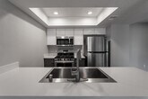 Located at 7600 Ambergate Pl in Riverside, California, this single-floor residence offers a clean, modern aesthetic with consistent wood-style flooring and neutral gray tones carried throughout every room. The open-concept living area is bright and spacious, with a sliding glass door that invites natural light and provides access to an outdoor space. The kitchen is thoughtfully designed with white upper cabinetry, a tray ceiling with recessed lighting, a white quartz countertop with an integrated sink, and a full suite of stainless steel appliances including a gas range, microwave, and refrigerator. Dark lower cabinetry adds a contemporary contrast to the overall design. The bedrooms are well-sized, each featuring ceiling fans and ample natural light. One bedroom includes mirrored sliding closet doors, offering convenient built-in storage. The bathroom is finished with a modern dark-toned vanity, white quartz countertop, a single sink, and a full tub-shower combination. Textured ceilings are present in several areas of the home, adding architectural character. The layout, as seen in the dollhouse view, flows efficiently, connecting living, kitchen, bedroom, and bathroom spaces in a practical and comfortable arrangement.