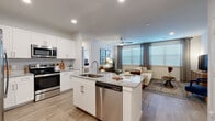 This thoughtfully designed single-floor residence offers 2 bedrooms, 3 bathrooms, and two closets within a comfortable and cohesive layout. The open-concept kitchen and living area serves as the heart of the home, featuring white shaker cabinetry, granite countertops, a large center island with a built-in sink and dishwasher, and stainless steel appliances including a range and over-the-range microwave. A subway tile backsplash and light wood-look flooring add a clean, modern aesthetic that flows seamlessly throughout the unit. The living room is bright and welcoming, benefiting from large windows dressed with horizontal blinds and draping curtains that invite natural light while offering privacy. A ceiling fan adds comfort to the space. The primary bedroom is a serene retreat of generous proportions, featuring a walk-in closet with wire shelving. Both bedrooms offer natural light through well-positioned windows. The bathrooms are finished with granite-topped white vanities, wood-look tile flooring, and full tub-shower combinations elegantly clad in large-format marble-style tile. The consistent use of light tones, quality finishes, and cohesive design elements throughout give this residence a polished, contemporary feel.