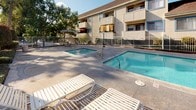 Located at 3161 W Ball Rd in Anaheim, California, this single-story property is part of a well-established residential community in the heart of Orange County. The exterior showcases a classic stucco and wood-trim façade with a neutral color palette, complemented by mature trees that provide natural shade throughout the grounds.

The outdoor amenities are a highlight of this property. A generously sized swimming pool takes center stage, surrounded by a spacious concrete deck furnished with white lounge chairs — ideal for relaxing in Southern California's sunny climate. A separate spa is also available, offering a more intimate retreat alongside the main pool. The pool area is fully enclosed by iron fencing for safety and privacy, with a dedicated utility structure nearby. An umbrella-shaded seating area adds further comfort to the outdoor space.

The surrounding landscape features tall, established trees that frame the property and contribute to a pleasant, shaded atmosphere. The overall setting reflects a comfortable, community-oriented environment with practical amenities suited for everyday living. Its Anaheim location provides convenient access to local shopping, dining, and entertainment destinations throughout the greater Orange County area.