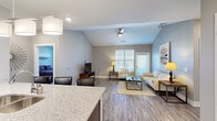 Located at 6131 Summit St in Shawnee, Kansas, this single-floor residence offers a thoughtfully designed open-concept layout finished with contemporary details throughout. The living area is a standout, boasting dramatic vaulted ceilings with a ceiling fan, wood-look luxury vinyl plank flooring, and large windows that invite abundant natural light. A sliding door provides outdoor access, enhancing the airy, open feel of the space.

The kitchen is well-equipped with rich dark-brown cabinetry, stainless steel appliances including a refrigerator, range, and microwave, a decorative tile backsplash, and light granite countertops. A peninsula with an undermount sink and bar seating offers a convenient space for casual dining and additional prep area.

The bedrooms are carpeted for comfort and feature neutral wall tones, ample natural light from double windows with blinds, and generous closet space with built-in shelving and hanging rods. The bathrooms mirror the kitchen's design aesthetic, showcasing dark wood vanities topped with granite countertops, large mirrors, wood-look flooring, and shower/tub combinations. Consistent use of soft gray tones, modern fixtures, and quality finishes throughout creates a cohesive, contemporary ambiance across the entire residence.