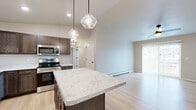 Located at 4216 N Lightning Dr in Appleton, WI, this well-appointed 2-bedroom, 2-bathroom single-floor residence offers a thoughtfully designed open layout. The combined kitchen and living area serves as the heart of the home, showcasing a central island with striking marble-look countertops illuminated by elegant pendant lighting. Dark espresso cabinetry contrasts beautifully with the light countertops and light-toned luxury vinyl plank flooring that runs throughout much of the space. A full suite of stainless steel appliances completes the kitchen. The living area is bright and airy, benefiting from a sliding glass door that floods the space with natural light and provides outdoor views, complemented by a ceiling fan overhead. The spacious primary bedroom features plush carpeting, a closet, and a large window with neighborhood views. The bathrooms mirror the kitchen's refined aesthetic with dark wood vanities, marble-look countertops, and light flooring. A dedicated laundry room with wire shelving and in-unit washer adds everyday convenience. Two closets provide ample storage, and a hallway connects the living spaces efficiently. The overall ambiance is clean, modern, and move-in ready.