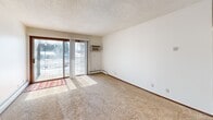 Located in Eagan, Minnesota, this one-bedroom, one-bathroom unit offers a functional and efficient single-floor layout. The galley-style kitchen features warm wood cabinetry, laminate countertops, hardwood-style flooring, and white appliances including a refrigerator, electric range, and dishwasher. Upper and lower cabinets provide ample storage, and the layout allows for a smooth workflow throughout the cooking space.

The combined kitchen and living area transitions into a carpeted living room that benefits from natural light streaming through a sliding glass door, which opens to an outdoor balcony with views of the surrounding landscape. Baseboard heating runs along the perimeter, and a ceiling fan adds additional comfort. The textured ceiling is consistent throughout the main living spaces.

The bedroom is a comfortable size, featuring plush carpet, a ceiling fan, a window with vertical blinds for natural light and privacy, and baseboard heating. Two closets serve the unit — one standard and one larger closet — offering generous storage for a space of this size.

The bathroom includes a full tub-shower combination with clean white tile surround. Overall, the unit presents a practical and well-organized floor plan suited for individuals or couples seeking a manageable, cozy living space in Eagan.