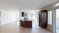 Located at 2100 Round Pointe Dr in Haverstraw, NY, this two-bedroom, two-bathroom residence is designed with a practical and modern layout across a single floor. The open-concept kitchen serves as a central highlight, featuring rich dark wood cabinetry, granite countertops, and a curved peninsula that seamlessly connects the kitchen to the adjacent living area. Stainless steel appliances, including a built-in microwave and full-size refrigerator, complement the space, while tile flooring in the kitchen transitions smoothly into warm hardwood-style flooring in the living area. Large windows throughout allow generous natural light to fill the interior, offering views of the surrounding greenery. The living area benefits from an open, airy feel with clean white walls and a bright, neutral palette that provides a versatile backdrop for any décor. The overall design balances functionality with comfort, making it a well-appointed home in the Round Pointe community of Haverstraw, conveniently positioned along the Hudson Valley region of New York.