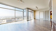 Located in the heart of downtown Austin at 101 Colorado St, this high-rise residence offers a refined urban living experience with sweeping panoramic views of the Austin skyline, Lady Bird Lake, and the surrounding cityscape. The open-concept living area is anchored by dramatic floor-to-ceiling windows that flood the space with natural light and frame breathtaking elevated views, with hardwood-style flooring flowing throughout. A private balcony extends the living space outdoors, offering an unobstructed vantage point over the city below. The kitchen is a standout feature, showcasing rich dark cabinetry, granite countertops, a large center island with built-in wine storage, pendant lighting, a tray ceiling with track lighting, and stainless steel appliances — all framed by an elegant arched entryway. The generously sized primary bedroom benefits from large windows with city views and connects to an expansive walk-in closet with full wire shelving systems. Two well-appointed bathrooms feature dark wood vanities, granite countertops, large mirrors, and stone tile flooring. A dedicated in-unit laundry room with side-by-side washer and dryer adds everyday convenience. With five closets and a utility room, storage is abundant throughout this thoughtfully designed downtown retreat.