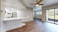 Located at 7610 W Waters Ave in Tampa, Florida, this thoughtfully designed single-floor unit makes excellent use of its intimate footprint. The open-concept layout connects the kitchen and living area seamlessly, creating a cohesive and functional living space. The kitchen is a standout feature, outfitted with stainless steel appliances including a range, microwave, dishwasher, and refrigerator. Crisp white cabinetry with subway tile backsplash lines the walls, while a peninsular island with a light granite-style countertop provides additional prep space and built-in shelving below. Durable wood-look flooring flows throughout the entire unit, adding warmth and continuity. The living area benefits from natural light streaming through a large window with blinds, and a sliding glass door leads to an outdoor access point. A ceiling fan with a light fixture keeps the space comfortable. The bathroom is clean and functional, featuring a full tub/shower combo with white surround. A textured ceiling adds subtle character throughout, and neutral warm-gray wall tones create a calm, modern ambiance suited for everyday living in Tampa's vibrant community.