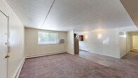 This single-floor, 2-bedroom, 1-bathroom residence in Levittown, PA offers a practical and well-organized layout with a comfortable sense of space throughout. The open living and dining area is carpeted and bathed in natural light from a window fitted with blinds, with a wall-mounted air conditioning unit providing added climate control. Baseboard heating runs throughout the home, ensuring year-round comfort. The kitchen is a standout feature, showcasing rich dark cabinetry, granite-style countertops, subway tile backsplash, stainless steel appliances including a refrigerator, range, and dishwasher, and durable wood-look vinyl flooring — all centered around a window overlooking the outdoors. Both bedrooms are generously proportioned with plush carpeting and feature closet space, with the primary bedroom offering a notably spacious feel and a double-door closet. The full bathroom is clean and functional, equipped with a white vanity, medicine cabinet mirror, and a well-lit vanity fixture. A hallway connects the rooms efficiently, and six closets throughout the home provide exceptional storage. The textured ceiling treatment is consistent across the space, adding a subtle architectural detail to each room.