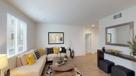 This well-designed single-floor residence offers a thoughtfully arranged open-concept layout that seamlessly connects the main living spaces. The living room is bright and welcoming, featuring large windows dressed with patterned curtains and horizontal blinds that invite generous natural light. Light wood-tone flooring runs throughout the main areas, complementing the neutral warm wall tones and creating a cohesive, modern aesthetic.

The kitchen is a standout feature, equipped with full stainless steel appliances including a gas range, built-in microwave, and refrigerator. Rich dark wood cabinetry extends to the ceiling for ample storage, and a white quartz island with bar seating serves as both a functional workspace and a casual dining spot, illuminated by pendant lighting above.

Adjacent to the kitchen, the dining area benefits from its own window, filling the space with natural light. The bedroom is a tranquil retreat with plush carpeting, a ceiling fan, and a window that provides a view of the surroundings. The bathroom features a dual-sink vanity with dark cabinetry, a white quartz countertop, a large mirror, and a full tub-shower combination with clean white tile surround. Throughout, the space maintains a clean, contemporary character with recessed lighting and modern finishes.