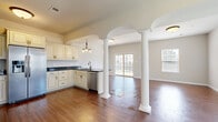 Located at 26 Delano Dr in Chambersburg, PA, this two-story home offers four bedrooms and two bathrooms thoughtfully distributed across two floors of comfortable living space. The main floor makes a strong first impression with its open-concept kitchen and living area, defined by striking white decorative columns beneath arched ceilings. Rich hardwood-style flooring flows throughout, while multiple windows and sliding glass doors flood the space with natural light and provide views of the outdoors. The kitchen features cream cabinetry with dark granite countertops, stainless steel appliances, and a built-in pantry with double doors for ample storage. A dedicated laundry room on the main floor is equipped with a washer, dryer, and utility sink. The carpeted staircase with a warm wood and wrought iron railing leads to the upper floor, where the spacious primary bedroom features a tray ceiling with crown molding and a generous walk-in closet with wire shelving. Additional bedrooms are bright and well-sized, each with plush carpet and natural light. The bathrooms are finished with dark granite vanities, cream cabinetry, and tub-shower combinations. Two hallways and additional closets throughout ensure practical storage, completing this well-designed home.