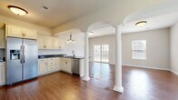 Located at 26 Delano Dr in Chambersburg, PA, this two-story home offers four bedrooms and two bathrooms thoughtfully distributed across two floors of comfortable living space. The main floor makes a strong first impression with its open-concept kitchen and living area, defined by striking white decorative columns beneath arched ceilings. Rich hardwood-style flooring flows throughout, while multiple windows and sliding glass doors flood the space with natural light and provide views of the outdoors. The kitchen features cream cabinetry with dark granite countertops, stainless steel appliances, and a built-in pantry with double doors for ample storage. A dedicated laundry room on the main floor is equipped with a washer, dryer, and utility sink. The carpeted staircase with a warm wood and wrought iron railing leads to the upper floor, where the spacious primary bedroom features a tray ceiling with crown molding and a generous walk-in closet with wire shelving. Additional bedrooms are bright and well-sized, each with plush carpet and natural light. The bathrooms are finished with dark granite vanities, cream cabinetry, and tub-shower combinations. Two hallways and additional closets throughout ensure practical storage, completing this well-designed home.