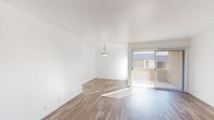 Located in Los Angeles, CA (91343), this single-floor residence offers a clean, functional layout finished consistently with rich wood-look flooring throughout every room. The open living area is bright and airy, featuring crisp white walls, a pendant light fixture, and a sliding glass door that invites natural light and provides access to an outdoor space. The galley-style kitchen is well-appointed with warm wood cabinetry, granite-look countertops, a double sink, and black appliances including a refrigerator, dishwasher, and range. An adjacent dining or flex area provides additional versatility. The bedrooms are generously sized with large windows fitted with blinds that allow for natural light and privacy. One bedroom includes a vanity area with a wood-toned cabinet and large mirror. The two bathrooms feature wood cabinetry with matching hardware — one with a tub/shower combination and another with a standalone corner shower stall. A dedicated laundry area houses a full-size washer and dryer beneath overhead white cabinetry for added storage. White walls and clean trim throughout the space lend a cohesive, neutral aesthetic well-suited to a variety of furnishing styles.