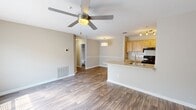 This single-floor residence offers a practical and comfortable layout across two bedrooms and four bathrooms. The open-concept living and kitchen area serves as the heart of the home, featuring durable wood-style flooring, neutral warm-toned walls, and a ceiling fan with integrated lighting. The kitchen is equipped with light maple cabinetry, a tile backsplash, black appliances including a range and refrigerator, and a peninsula with a granite-style countertop and single-basin sink — ideal for both cooking and casual dining. The living area benefits from natural light through window blinds and connects seamlessly to the rest of the unit. The primary bedroom offers generous proportions, plush carpeting, a large window with natural light, and access to a closet. The second bedroom is similarly appointed with soft carpet flooring and ample wall space. The bathrooms feature wood-style flooring, light wood vanities with white countertops, tub-shower combinations with tiled surrounds, and well-lit mirrors. A dedicated laundry room houses a full-sized washer and dryer. The space maintains a clean, cohesive aesthetic throughout with consistent neutral tones and functional finishes.