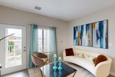 This well-appointed one-bedroom, one-bathroom residence in Clinton Township, Michigan offers a thoughtfully designed layout with modern finishes throughout. The open-concept living and kitchen area serves as the heart of the home, bathed in natural light from large windows dressed with airy teal curtains. Light wood-look flooring runs seamlessly through the main living space, complementing the neutral, warm-toned walls.

The kitchen is a standout feature, equipped with stainless steel appliances, sleek taupe cabinetry, crisp white countertops, and a peninsula with bar seating — ideal for casual dining or entertaining. Recessed lighting illuminates the space, adding a polished touch.

The living area is generously proportioned, offering room for a full seating arrangement and direct access to a private balcony with outdoor views. The bedroom is a comfortable retreat with plush carpeting, large windows allowing ample natural light, and a dedicated closet for storage.

The bathroom is cleanly finished with tile flooring, a warm wood vanity with white countertop, and an LED-backlit mirror. Throughout the space, consistent neutral tones, quality materials, and modern design choices create a cohesive and inviting ambiance.
