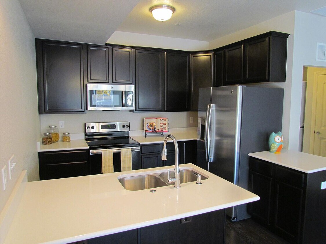 Kitchen has white quartz countertops, cherry finish cabinets, and stainless steel appliances. - 3800 Manhattan Ave
