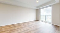 Located at 660 Sunningdale Rd E in London, Ontario, this well-appointed one-bedroom unit offers a clean, modern aesthetic with thoughtful design throughout. Light-toned hardwood flooring flows consistently across the entire space, lending a warm and cohesive feel to every room.

The open-concept kitchen and living area serves as the heart of the unit. The kitchen features crisp white upper cabinetry, a light-coloured quartz countertop with a breakfast bar peninsula finished in a soft blue accent, stainless steel appliances including a full-size refrigerator and built-in microwave, and pendant lighting overhead — creating a functional and stylish cooking space.

The spacious primary bedroom is generously sized, featuring floor-to-ceiling sliding glass door access and tall double windows that flood the room with natural light and offer expansive views of the surrounding London cityscape and neighbourhood below. The bright, neutral wall tones throughout complement the airy atmosphere.

A hallway connects the living areas to a bathroom, with a closet nearby providing practical storage. The unit's clean lines, recessed lighting, and neutral palette give the space a fresh, move-in-ready appeal. Overall, this unit combines modern finishes with abundant natural light and elevated views for a comfortable urban living experience.