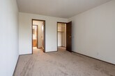 This single-floor residential unit offers a practical and straightforward layout designed for comfortable everyday living. The main living area is finished with neutral-toned carpet and features a ceiling fan, providing a simple and functional space. A wood-paneled entry door adds a classic touch to the entryway.

The kitchen is equipped with cream-colored cabinetry, dark laminate countertops, a double stainless steel sink, a dishwasher, and a full-size refrigerator, all set atop durable tile flooring that contrasts with the carpeted areas throughout the rest of the unit.

The bedrooms are well-proportioned, each featuring plush carpet, vertical blinds over windows that invite natural light, and baseboard heating units along the walls. One bedroom includes an expansive open closet system with built-in shelving and multiple hanging rods, offering ample storage.

The unit includes two bathrooms. The full bathroom features a tub and shower combination with classic yellow tile surround, mosaic tile flooring, and a toilet. The second bathroom offers a vanity with a wood-framed mirror, a single-basin sink, chrome fixtures, and accessory bars. Both bathrooms maintain a clean, functional aesthetic suited for daily use.