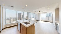 Located in the heart of downtown Dallas at 300 N Field St, this elevated three-bedroom, three-bathroom residence delivers a refined urban living experience with sweeping city skyline views. The open-concept living and kitchen area is anchored by light hardwood flooring, floor-to-ceiling windows, and a tray ceiling that adds architectural depth. The chef's kitchen is appointed with warm wood cabinetry, stainless steel appliances, and a striking marble-topped island, all framed by panoramic views of the Dallas skyline including the iconic Reunion Tower. The spacious primary bedroom features plush carpeting, a ceiling fan, and a well-appointed en-suite bathroom with large-format tile flooring, a frameless glass walk-in shower with marble tile surround, and a vanity with modern gold hardware. Additional bedrooms are generously sized, each benefiting from abundant natural light and sweeping city views through expansive windows. Two walk-in closets provide excellent storage with built-in shelving and hanging rods. The dedicated laundry area houses a full-size side-by-side washer and dryer. Clean neutral tones, dark baseboards, and recessed lighting throughout lend the residence a cohesive, contemporary aesthetic ideal for downtown living.