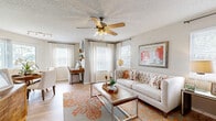 This single-story, 2-bedroom, 2-bathroom home delivers a practical and inviting layout designed for comfortable everyday living. The open-concept living room is a bright, welcoming space featuring hardwood-style flooring, multiple windows dressed with blinds and sheer curtains, and a ceiling fan overhead. The adjacent dining area benefits from a sliding glass door that floods the space with natural light and offers a pleasant outdoor view of lush greenery. The kitchen is well-equipped with light wood cabinetry, dark granite-style countertops, a tile backsplash, and a full suite of black appliances including a refrigerator, range, microwave, and dishwasher. A dedicated laundry area and closet add convenience to the floor plan. The primary bedroom is a generously sized retreat with plush carpeting, a ceiling fan, and a bold teal accent wall that adds a pop of color, complemented by built-in closet storage. The second bedroom also features carpeting, a ceiling fan, and direct sightlines to the living area. Both bathrooms are clean and functional — one featuring wood-tone cabinetry with a dark countertop and hardwood-style flooring, and the other with a tiled tub-shower combination. Textured ceilings are present throughout the home.