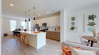 This contemporary two-story residence offers a thoughtfully designed layout with clean lines and modern finishes throughout. The open-concept main floor centers around a sleek kitchen equipped with stainless steel appliances, two-tone cabinetry featuring white uppers and warm wood-grain lowers, a subway tile backsplash, and a generous island with a white quartz countertop and pendant lighting overhead — ideal for casual dining or entertaining. Light wood-tone flooring flows seamlessly into the adjacent living area, which is bright and airy thanks to large windows and sliding glass doors. A dedicated dining area sits nearby, bathed in natural light from multiple windows and accented by neutral walls that complement the space's modern aesthetic. A full bathroom with wood-grain vanity cabinetry is conveniently located on the main level. Upstairs, the bedrooms offer plush carpeting and ample natural light through well-proportioned windows. The primary bedroom is spacious and connects to an en-suite bathroom featuring a double-sink vanity, a glass-enclosed walk-in shower, and wood-finish cabinetry. An additional full bathroom with a single vanity and shower serves the remaining bedrooms. Throughout, the design maintains a cohesive, contemporary palette of whites and warm wood tones, creating a bright and welcoming atmosphere.