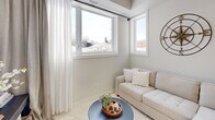 Located at 192 Erie St in Port Colborne, Ontario, this thoughtfully designed 2-bedroom, 1-bathroom unit offers a clean, contemporary aesthetic with a neutral palette and modern finishes throughout. The open-concept main living area seamlessly connects the kitchen, dining, and living spaces, creating an efficient yet welcoming atmosphere. The kitchen is a standout feature, boasting crisp white cabinetry, stainless steel appliances, and a generous quartz countertop island with bar seating — ideal for casual dining or entertaining. Light hardwood-style flooring runs through the main area, complementing the bright, airy feel enhanced by recessed pot lighting. A large decorative mirror in the dining area adds depth to the space. The living area benefits from oversized windows that flood the room with natural light and offer views of the surrounding neighbourhood. Both bedrooms are carpeted for comfort, each featuring windows with outdoor views and ample room for standard furnishings. The primary bedroom is a calm retreat with neutral tones and soft drapery. The bathroom is finished with wood-look tile flooring, a tub-shower combination with marble-style surround, and open shelving for practical storage. This unit offers a polished, move-in-ready living experience in a compact and well-appointed package.