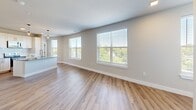 This well-appointed 2-bedroom, 2-bathroom residence in Nashville's Wedgewood neighborhood offers a thoughtfully designed single-floor layout. The open-concept living and kitchen area is filled with natural light from multiple large windows fitted with sleek white blinds, offering views of the surrounding greenery. Warm hardwood-style flooring runs throughout the main living spaces, complementing the neutral, light-toned walls that lend a clean, modern aesthetic.

The kitchen is a standout feature, boasting white shaker-style cabinetry extending floor to ceiling, granite countertops, a stainless steel appliance suite including a refrigerator, range, microwave, and dishwasher, and a central island for added prep space.

Both bedrooms are generously sized, featuring plush carpet flooring and ceiling fans. The primary bedroom includes a window with outdoor views and direct access to its own en-suite bathroom, which is equipped with a spacious walk-in glass-enclosed shower, a granite-topped vanity, and hardwood-style flooring. The secondary bathroom mirrors this quality with a full tub-shower combo and matching finishes.

A dedicated in-unit laundry room with a full-size Whirlpool washer and dryer adds everyday convenience. Three closets provide ample storage throughout the home.