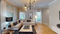 This single-floor residence offers a thoughtfully designed layout with a neutral warm palette and consistent hardwood flooring connecting the main living areas. The living room is bright and welcoming, benefiting from multiple windows that invite natural light, and is anchored by a contemporary branch-style chandelier and crown molding details. Adjacent to it, the dining area features a round glass table beneath a classic dome pendant light, with large windows offering outdoor views.

The kitchen is outfitted with rich dark cabinetry, light stone countertops, a cream tile backsplash, and stainless steel appliances, including a french-door refrigerator. A louvered-door closet provides convenient pantry storage nearby.

The primary bedroom is spacious, featuring carpet flooring, crown molding, a ceiling fan, and generous natural light through wide windows. It includes a walk-in closet. A second bedroom offers a similarly comfortable layout with decorative wall accents and good natural light.

Two full bathrooms serve the residence, each featuring a tub-shower combination. One bathroom has light hardwood flooring with a framed window, while the second features white subway tile and a dark vanity. The overall ambiance is clean, modern, and cohesive throughout.