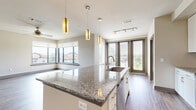 Located on Memorial Drive in Houston's 77079 corridor, this well-appointed 2-bedroom, 2-bathroom residence offers a thoughtfully designed single-floor layout. The open-concept kitchen and living area serves as the heart of the home, showcasing a large granite island with pendant lighting overhead, white shaker cabinetry, a sleek tile backsplash, stainless steel appliances, and track lighting. Rich hardwood-style flooring runs throughout the main living areas, adding warmth and continuity.

The living area is bathed in natural light through expansive corner windows that frame outdoor views of the surrounding neighborhood. A ceiling fan adds comfort to the bright, airy atmosphere.

The primary bedroom is generously sized, featuring corner windows, hardwood-style flooring, and a ceiling fan. Its en-suite bathroom is well-appointed with a dual-sink granite vanity, a soaking tub, and a separate glass-enclosed shower with tile surround. The second bedroom offers plush carpeting, dual windows with neighborhood views, and a ceiling fan. Five closets throughout the residence provide abundant storage. Additional highlights include an in-unit laundry, a hallway connecting all rooms efficiently, and a private balcony perfect for enjoying the outdoors.