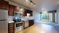 Located at 3029 22nd Ave S in Minneapolis, MN, this one-bedroom, one-bathroom unit offers a well-designed layout that maximizes functionality and comfort. The open-concept living area seamlessly connects the kitchen, dining, and living spaces, all finished with warm light hardwood flooring. The kitchen is a standout feature, equipped with rich dark-wood cabinetry, granite-style countertops, and a full suite of stainless steel appliances including a range, microwave, dishwasher, and refrigerator, all illuminated by sleek track lighting overhead. The living area extends naturally toward a sliding glass door that opens onto a private balcony, bringing in generous natural light. The carpeted bedroom offers a calm, neutral retreat with a window for additional natural light, and connects to a large walk-in closet outfitted with wire shelving and hanging rods for ample storage. The bathroom features a full tub-shower combination with clean white surround and hardwood-style flooring. An in-unit laundry area adds everyday convenience. Neutral tones and clean finishes throughout create a cohesive, move-in-ready atmosphere.