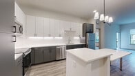 This well-designed 2-bedroom, 2-bathroom residence offers a thoughtfully laid-out single floor plan with clean, contemporary finishes throughout. The open-concept kitchen and living area serves as the heart of the home, featuring a striking two-tone cabinet design with crisp white upper cabinets and charcoal lower cabinets, white quartz countertops, a classic subway tile backsplash, and a full suite of stainless steel appliances. A central island with an extended breakfast bar provides additional prep and dining space, while a modern multi-pendant chandelier adds a refined touch overhead. Light wood-look flooring flows seamlessly through the entire residence, complementing the neutral, warm-toned walls. Both bedrooms are generously proportioned, bright, and tranquil, with large windows that welcome natural light and offer views of the surrounding outdoor amenity spaces. The primary bedroom is accompanied by a walk-in closet outfitted with multi-tier wire shelving for ample storage. The bathrooms echo the modern aesthetic with gray vanity cabinetry, white quartz countertops, and sleek matte black hardware. A dedicated laundry area with a stacked washer and dryer is also included. The overall ambiance is clean, bright, and move-in ready.