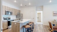 Located at 2025 E Carlson St in Cheyenne, WY, this well-designed 2-bedroom, 2-bathroom unit offers a thoughtfully planned single-floor layout with modern finishes throughout. The open-concept living area features warm wood-look flooring, a ceiling fan, and natural light streaming through windows with clean white blinds, creating a bright and welcoming atmosphere.

The kitchen is a standout feature, equipped with wood-toned cabinetry, white quartz countertops, stainless steel appliances including a refrigerator, range, microwave, and dishwasher, and a peninsula island with bar seating — ideal for casual dining and entertaining.

Both bedrooms are comfortably sized, with the primary bedroom offering a walk-in closet complete with built-in shelving. The bedrooms feature plush carpeting and natural light from windows, providing a cozy retreat. Each of the two bathrooms includes wood-finish vanity cabinetry, white quartz countertops, large mirrors, and hardwood-style flooring, maintaining the home's consistent modern aesthetic.

Additional highlights include a dedicated laundry room and a walk-in closet with ample shelving for storage. The clean, neutral color palette and contemporary finishes throughout give this unit a fresh, move-in-ready appeal.