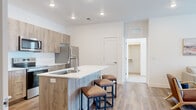 Located at 2025 E Carlson St in Cheyenne, WY, this well-designed 2-bedroom, 2-bathroom unit offers a thoughtfully planned single-floor layout with modern finishes throughout. The open-concept living area features warm wood-look flooring, a ceiling fan, and natural light streaming through windows with clean white blinds, creating a bright and welcoming atmosphere.

The kitchen is a standout feature, equipped with wood-toned cabinetry, white quartz countertops, stainless steel appliances including a refrigerator, range, microwave, and dishwasher, and a peninsula island with bar seating — ideal for casual dining and entertaining.

Both bedrooms are comfortably sized, with the primary bedroom offering a walk-in closet complete with built-in shelving. The bedrooms feature plush carpeting and natural light from windows, providing a cozy retreat. Each of the two bathrooms includes wood-finish vanity cabinetry, white quartz countertops, large mirrors, and hardwood-style flooring, maintaining the home's consistent modern aesthetic.

Additional highlights include a dedicated laundry room and a walk-in closet with ample shelving for storage. The clean, neutral color palette and contemporary finishes throughout give this unit a fresh, move-in-ready appeal.
