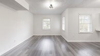 This thoughtfully designed single-floor residence offers a comfortable and modern living experience across its well-organized layout. The space is unified throughout by durable grey-toned hardwood-style flooring and crisp white walls, creating a clean, contemporary aesthetic.

The open-concept kitchen and living area serves as the heart of the home. The kitchen is outfitted with sage green shaker-style cabinetry, a marble-look quartz peninsula countertop, stainless steel appliances including a gas range and full-size refrigerator, and a gold-accented sink. A stylish sputnik chandelier adds a modern design touch overhead. The adjoining living room benefits from natural light through multiple windows and offers a flexible, open layout.

The bedroom is a well-proportioned, bright room featuring a built-in closet, large windows with outdoor views, and the same consistent flooring found throughout the unit. The neutral palette provides a calm, restful atmosphere.

The bathroom features large-format grey tile surround walls, a soaking tub with an overhead multi-function shower, matte black fixtures, and a pedestal sink, combining both style and function. A dedicated closet provides additional storage. The textured ceilings and crown molding details throughout add subtle architectural character to this move-in-ready space.