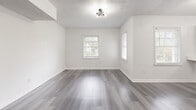 This thoughtfully designed single-floor residence offers a comfortable and modern living experience across its well-organized layout. The space is unified throughout by durable grey-toned hardwood-style flooring and crisp white walls, creating a clean, contemporary aesthetic.

The open-concept kitchen and living area serves as the heart of the home. The kitchen is outfitted with sage green shaker-style cabinetry, a marble-look quartz peninsula countertop, stainless steel appliances including a gas range and full-size refrigerator, and a gold-accented sink. A stylish sputnik chandelier adds a modern design touch overhead. The adjoining living room benefits from natural light through multiple windows and offers a flexible, open layout.

The bedroom is a well-proportioned, bright room featuring a built-in closet, large windows with outdoor views, and the same consistent flooring found throughout the unit. The neutral palette provides a calm, restful atmosphere.

The bathroom features large-format grey tile surround walls, a soaking tub with an overhead multi-function shower, matte black fixtures, and a pedestal sink, combining both style and function. A dedicated closet provides additional storage. The textured ceilings and crown molding details throughout add subtle architectural character to this move-in-ready space.