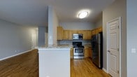 Located at 80 Jefferson Blvd in Fishkill, NY, this two-bedroom, two-bathroom residence is thoughtfully arranged on a single floor, offering a comfortable and functional living environment. The kitchen serves as a standout feature, showcasing warm honey-toned cabinetry that extends to the upper walls, providing generous storage throughout. Granite-look countertops add a refined touch, while stainless steel appliances — including a gas range, built-in microwave, and refrigerator — equip the space for everyday cooking. A white breakfast bar peninsula extends from the kitchen, creating a natural divide between the cooking area and the adjoining living space, while also offering a casual seating or serving area. Hardwood-style flooring flows consistently throughout, lending warmth and visual continuity to the home. The neutral gray wall tones complement the cabinetry and flooring, creating a cohesive and understated palette. The open layout promotes an easy flow between the kitchen and living areas, making the space feel welcoming and versatile. With two full bathrooms and two bedrooms, this residence offers practical accommodations suited for a range of lifestyles.