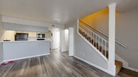 Located at 2909 Hayes Rd in Houston, TX, this two-story, one-bedroom, two-bathroom home offers a well-organized layout spread across two floors. The main level features an open-concept living and dining area with wood-look laminate flooring and a vaulted ceiling that rises dramatically to the second floor, filling the space with natural light through a large bank of windows. The kitchen is efficiently designed with gray cabinetry, white quartz-style countertops, a tile backsplash, and black appliances including a refrigerator, range, and over-the-range microwave. A staircase with white railings leads to the upper level, which is carpeted throughout. The generously sized primary bedroom features a vaulted ceiling with interior clerestory windows that borrow light from the living area below, creating an open, airy feel. A walk-in closet with built-in shelving and hanging rods provides ample storage. Both bathrooms feature wood-look flooring, light gray vanities with white countertops, and clean, neutral finishes. The home's consistent use of gray tones, white trim, and modern fixtures gives it a cohesive, updated aesthetic throughout.