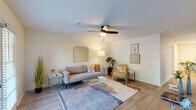 This single-floor residence offers a well-designed layout with a cohesive, modern aesthetic throughout. The living room serves as the heart of the space, featuring wood-look flooring, a ceiling fan with light fixture, and French doors that open to an outdoor view, allowing natural light to fill the room. The open-concept kitchen is equipped with stainless steel appliances, including a full-size refrigerator and gas range, complemented by white subway tile backsplash, light cabinetry, a peninsula with pendant lighting, and a skylight above that brightens the cooking area. Adjacent to the kitchen, a dedicated dining nook provides a comfortable space for casual meals. A hallway connects the living areas to the bedroom, with a reach-in closet accessible nearby. The bedroom is carpeted for comfort and includes a ceiling fan, a window with blinds that invites natural light, and a spacious closet. The full bathroom features a single-sink vanity with ample cabinet storage, a tiled tub-shower combination, and wood-look flooring. Throughout the unit, neutral walls and consistent flooring create a clean, inviting atmosphere.