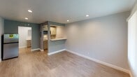 Located at 2630 W Lincoln Ave in Anaheim, California, Room 240 is a thoughtfully designed single-floor unit that offers a clean, modern aesthetic throughout. The main living area is open and airy, finished with light wood-look luxury vinyl flooring that runs seamlessly throughout the space, paired with soft gray-blue accent walls and crisp white baseboards that give the interior a fresh, contemporary feel. Recessed lighting illuminates the living area evenly, enhancing the bright and welcoming ambiance.

The kitchenette is efficiently laid out and features white shaker-style cabinetry, a white countertop with a stainless steel sink, an electric cooktop, and an over-the-range microwave. A pass-through counter bar connects the kitchen to the living area, promoting an open, functional flow between the two spaces. A stainless steel refrigerator completes the kitchen setup.

The bedroom is a well-proportioned private space, also finished with matching flooring and neutral walls. A single recessed light and a window provide both artificial and natural illumination, while a dark-toned entry door adds a subtle design contrast.

The bathroom offers a clean, minimalist finish with a single-sink vanity topped with a white countertop, a framed mirror, chrome fixtures, and an open closet rod — ideal for storage and everyday convenience. The unit presents a move-in-ready, polished environment suitable for a variety of uses.