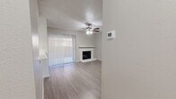 This single-story, 1-bedroom, 1-bathroom residence offers a thoughtfully designed layout that maximizes functionality and comfort. The open-concept main living area seamlessly combines the living room, dining room, and kitchen into one cohesive space. The living room is highlighted by a classic brick fireplace, a ceiling fan with light fixture, and a large sliding glass door dressed with vertical blinds that invites natural light and provides outdoor access. Light-toned laminate flooring runs throughout, complementing the neutral gray walls and white trim for a clean, modern aesthetic. The kitchen features white cabinetry, light granite-style countertops, a black electric range with overhead exhaust hood, and a window that brings in additional natural light. The bedroom is generously sized, equipped with its own ceiling fan, a large window, and access to ample closet space, including a walk-in closet with built-in shelving and hanging rods. Additional storage is provided through multiple closets and a dedicated pantry. The bathroom is finished with a full-size tub and shower combo, a toilet, and white cabinetry. A textured ceiling detail is present throughout the living areas, adding a subtle architectural touch to this well-organized and efficiently designed home.