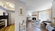 This single-floor residence offers a thoughtfully designed layout that balances comfort and functionality across its key living areas. The main living room serves as the heart of the home, featuring wood-look flooring, a white brick fireplace with a wooden mantel, and a large sliding glass door that floods the space with natural light. A dedicated workspace area flows seamlessly from the living room, adding versatility to the open floor plan. The entryway welcomes visitors with warm wood-look flooring and convenient access to the kitchen, which features a pass-through breakfast bar with seating, white cabinetry, granite-style countertops, and stainless steel appliances. The bedroom is carpeted for comfort and equipped with a ceiling fan, windows with blinds, and ample natural light. The bathroom is outfitted with a white vanity, granite-style countertop, framed mirror, and built-in storage shelving. Throughout the residence, textured ceilings, neutral wall tones, and consistent wood-look flooring create a cohesive and inviting aesthetic. The combination of functional spaces, warm finishes, and natural light makes this a comfortable and well-rounded living environment.