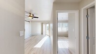 Located at 5560 Library Ln in Colorado Springs, Colorado, this two-bedroom, one-bathroom residence offers a bright and functional single-floor layout with a clean, modern aesthetic throughout. Light-toned hardwood-style flooring runs continuously across all rooms, lending a sense of openness and cohesion to the space.

The living area is a standout, featuring a ceiling fan, a striking white barn door with a matte black sliding track, and a sliding glass door that opens to a private balcony with views of the surrounding Colorado landscape. Natural light pours in through vertical blinds, creating a warm and airy atmosphere.

The galley-style kitchen is efficiently designed with white shaker cabinetry, white countertops, a stainless steel sink, and a full suite of stainless steel appliances including a refrigerator, electric range, and over-the-range microwave.

Both bedrooms are comfortably proportioned, each equipped with a ceiling fan, a closet with sliding or hinged doors offering ample storage, and windows dressed with vertical blinds that allow for generous natural light. The primary bedroom includes access to the balcony.

The bathroom features subway tile surrounding the bathtub and shower, a white vanity with storage, and consistent light wood flooring. Baseboard heating is present throughout the home, providing efficient warmth during Colorado's cooler seasons.
