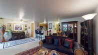This single-floor residence offers a thoughtfully arranged layout filled with character and eclectic décor throughout. The open living area serves as the heart of the home, featuring plush carpeting, ornate Persian-style area rugs, and a dark sofa accented with rich red and patterned throw pillows. A wooden curio cabinet displays decorative collectibles, and art pieces adorn every wall, lending a distinctive, gallery-like atmosphere. The space flows naturally into a secondary sitting area, where a bold marlin mount and large framed artwork create a striking focal point near the entry.

The kitchen is outfitted with warm oak cabinetry, ample counter space, a stainless steel sink, and black appliances, including a dishwasher. A raised bar with black stools provides casual seating and connects the kitchen to the main living area.

The primary bedroom features soft carpeting, a ceiling fan, a window with natural light, and closets with mirrored sliding doors. The carved wooden sleigh bed serves as a standout architectural feature of the room. A second bedroom offers similar comfort with its own mirrored closet and decorative fan wall art. Both bathrooms include a tub-shower combination, wooden vanity cabinetry, and tile flooring, providing clean, functional finishes throughout.