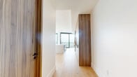 Located at 4855 S Quebec St in Denver, CO, this contemporary high-rise residence offers a refined living experience defined by clean lines, premium finishes, and sweeping panoramic views of the Denver skyline and surrounding landscape. Light oak hardwood flooring runs throughout the open-plan interior, complementing the crisp white walls and black-framed floor-to-ceiling windows that flood every room with natural light.

The combined kitchen and living area serves as the centerpiece of the space. The chef's kitchen is outfitted with rich wood cabinetry, slate-blue upper cabinets, stainless steel appliances including a gas range and double ovens, and a generous waterfall-edge quartz island with an undermount sink and elegant pendant lighting above.

The bedroom features the same wide-plank hardwood flooring and large windows framing elevated city views, accompanied by a dedicated closet. Both bathrooms are finished with large-format marble-look tile flooring and warm wood vanities, with the primary bath offering a glass-enclosed shower and an additional window capturing the elevated outlook.

Throughout the residence, warm wood door surrounds and matte black hardware provide thoughtful contrast to the otherwise light and airy palette, creating a sophisticated and cohesive modern aesthetic.