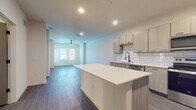 Located at 7701 Interbay Blvd in Tampa, FL, this single-floor residence offers a thoughtfully designed open-concept layout with clean, modern finishes throughout. Wide-plank wood-style flooring flows seamlessly across the living areas, creating a cohesive and contemporary aesthetic.

The kitchen serves as a central hub of the space, featuring light wood-toned cabinetry, a crisp white subway tile backsplash, and a generous island with a bright white countertop ideal for meal prep or casual dining. Stainless steel appliances — including a refrigerator, range, microwave, and dishwasher — complement the modern design, while a matte black faucet adds a refined contrast.

The open living area is bathed in natural light from large windows dressed with clean white blinds, and a ceiling fan provides both style and function. The layout connects rooms effortlessly, allowing for flexible use of space.

The bathroom is a standout feature, showcasing a dual-sink vanity with granite-style countertops, light wood cabinetry, and two LED-backlit mirrors that lend a spa-like ambiance. A soaking tub with matte black fixtures and large-format tile surround completes the retreat-like feel.

Throughout the residence, recessed lighting, neutral white walls, and consistent flooring create a bright, airy atmosphere well-suited to modern living in the heart of Tampa.