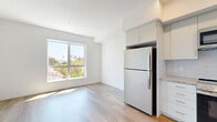 Located at 18900 Parthenia St in Northridge, Los Angeles, this well-designed one-bedroom, one-bathroom unit offers a thoughtful layout that maximizes every square foot. The open living and kitchen area is anchored by warm hardwood-style flooring that extends throughout the unit, creating a cohesive and inviting atmosphere. The modern kitchen is a standout feature, equipped with stainless steel appliances including a range, microwave, and dishwasher, complemented by white cabinetry, granite-style countertops, and a classic subway tile backsplash. Recessed lighting overhead keeps the space bright and functional. A hallway connects the main living area to the private bedroom, which is bathed in natural light from a large window. The bedroom features a spacious sliding-door closet, offering generous storage. The bathroom is clean and contemporary, finished with large-format floor tiles and a full tub-shower combination with marble-style surround walls. Throughout the unit, the crisp white walls and minimalist design create a modern, move-in-ready aesthetic that is both practical and stylish.